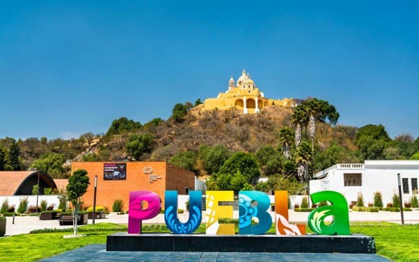 Letras monumentales de Puebla con una de las iglesias más emblemáticas de la ciudad.